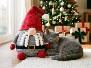 Cute cat resting by plush crochet Christmas gnome pillow