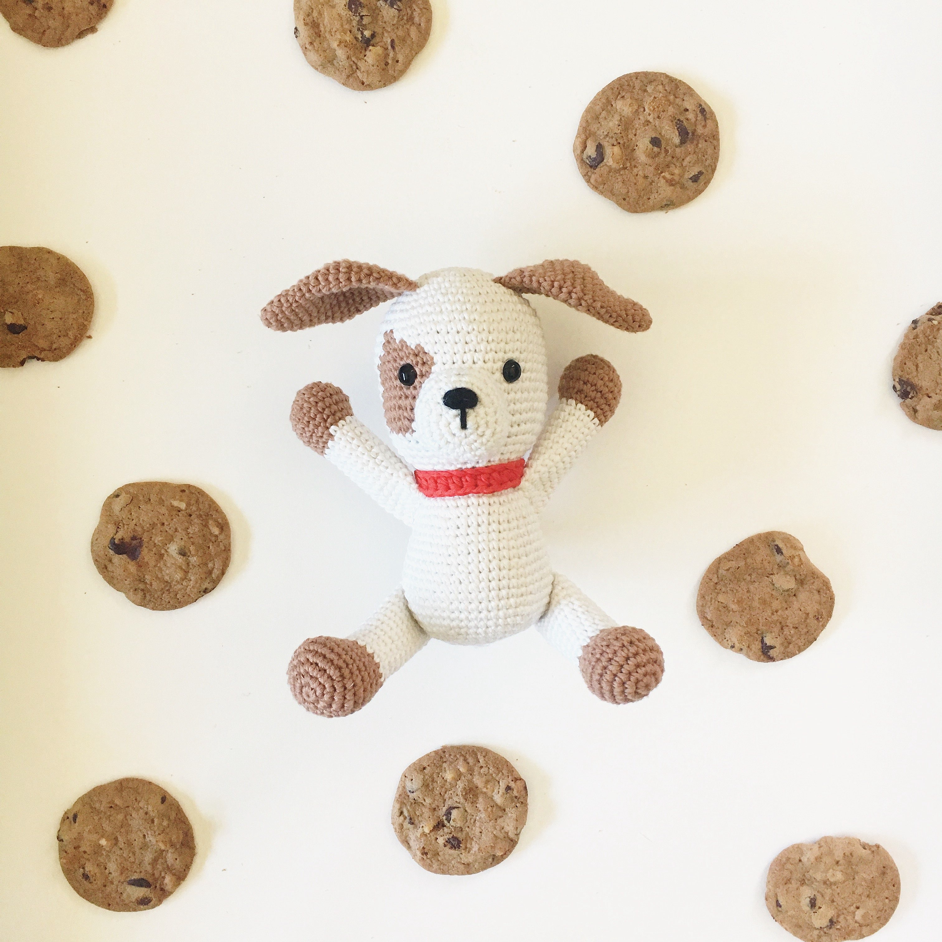 Handmade crochet puppy dog Puppy Chip with brown spotty eye patch and red collar studio display