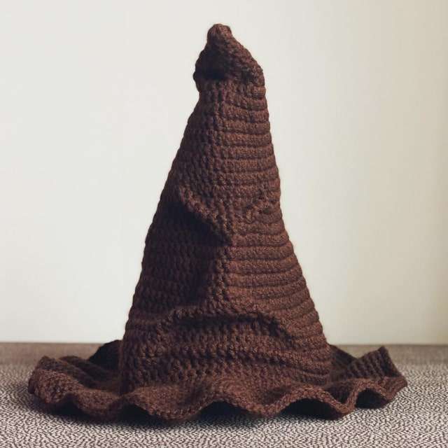 Standalone brown crochet Sorting Hat showing sculpted face features and wide brim