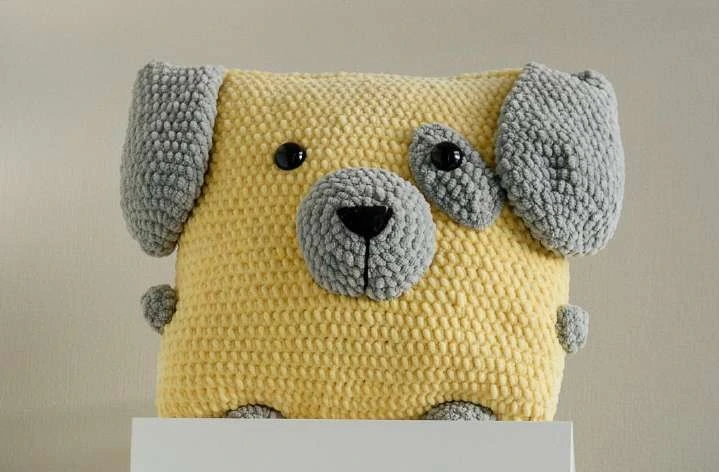 Handmade floppy-eared crochet dog pillow cushion styled on living room armchair