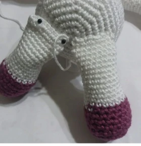 Pinning the crochet unicorn legs to the lower body to shape the sitting pose