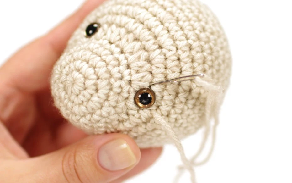 Demonstration of needle sculpting eye sockets and embroidering the nose on a crochet teddy bear